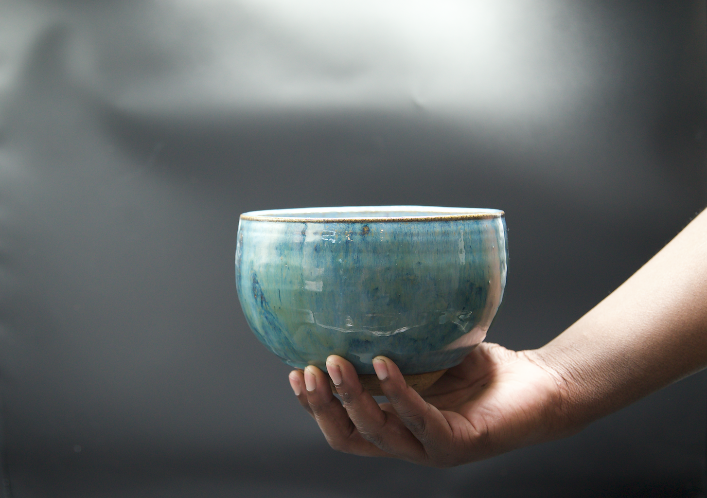 turquoise bowl being held with black backround